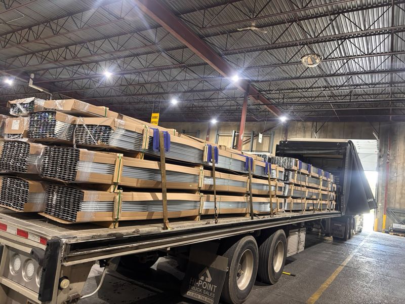 Boxed aluminum extrusions strapped on a Fission flatbed inside a loading dock