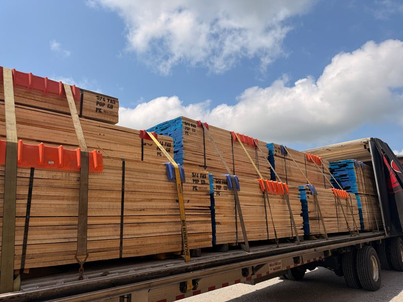 Lumber bundles strapped with edge protectors on a Fission open flatbed