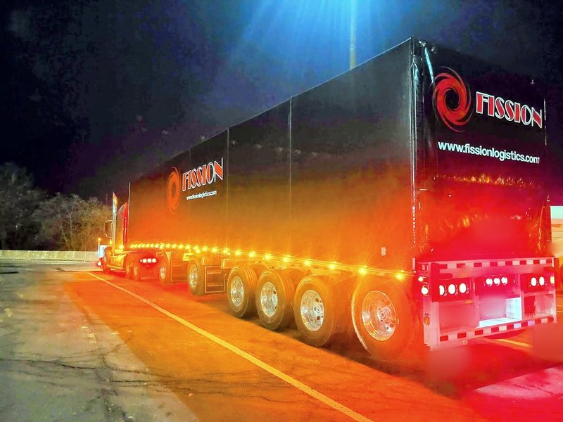 Fission multi axle trailer with its lights on at night, rear view